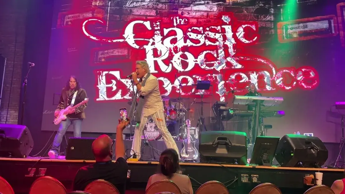 The Classic Rock Experience on a theater stage in front of its lit sign