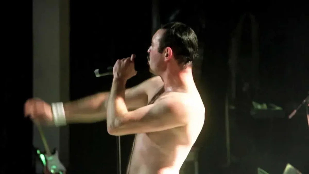 Gary Mullen performing as Freddie Mercury in One Night of Queen, shirtless with a microphone