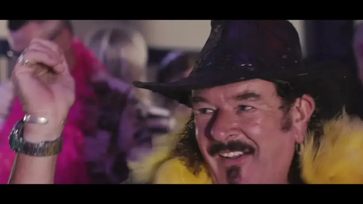 Rob Lea of Majesty, the UK Queen tribute band, in costume with a purple hat and yellow feather boa