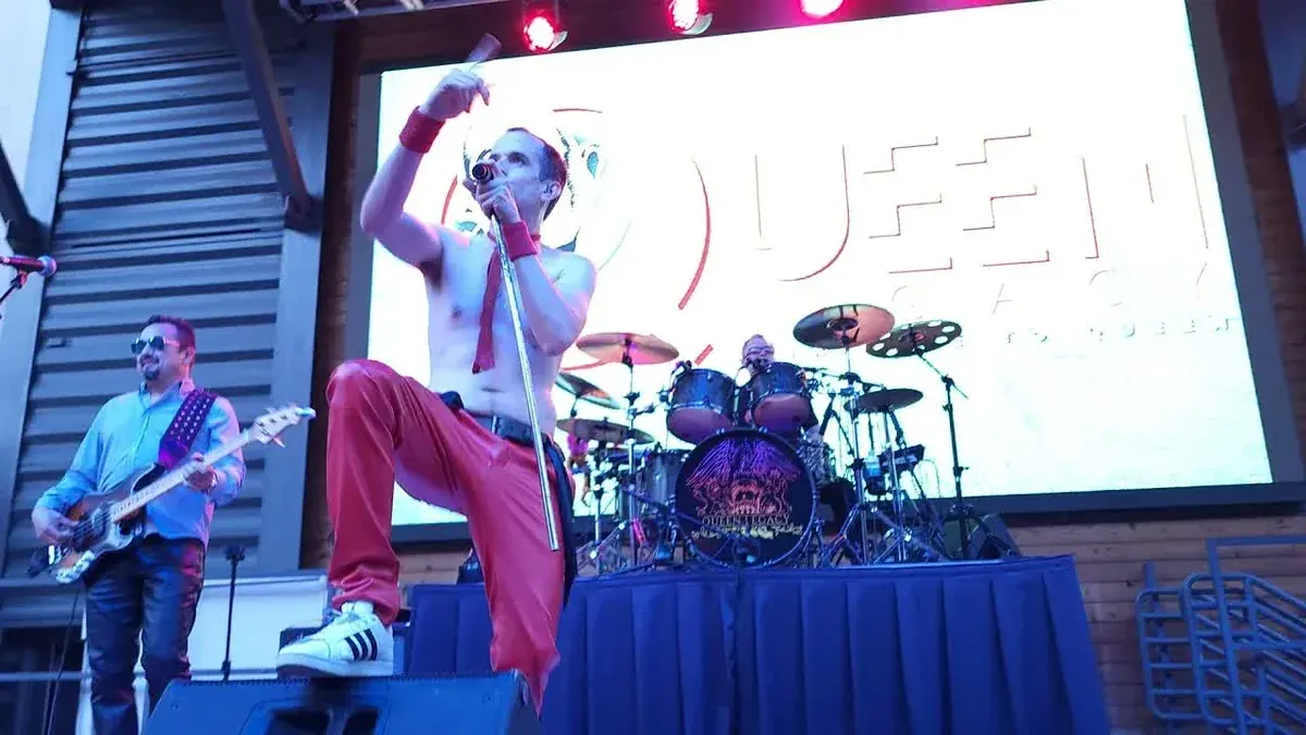 Queen Legacy singer Kyle Cousins as Freddie Mercury with bassist and drummer at Legacy Hall in Plano, Texas