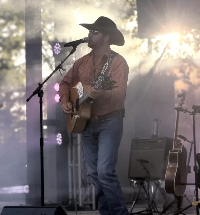 Chad Bushnell of Thunder Rolls singing and playing acoustic guitar on an outdoor stage
