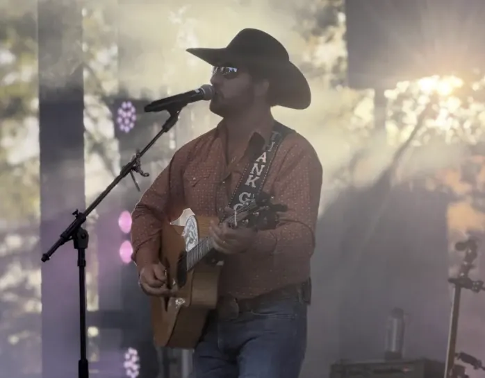 Chad Bushnell as Garth Brooks, singing with an acoustic guitar on stage in Thunder Rolls